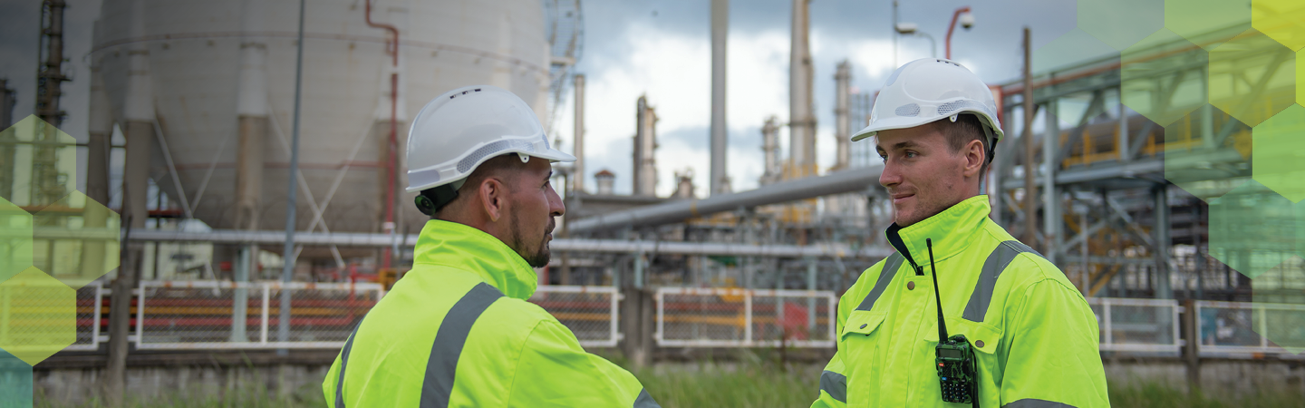 头戴安全帽、身穿荧光色背心的两位工作人员正在握手